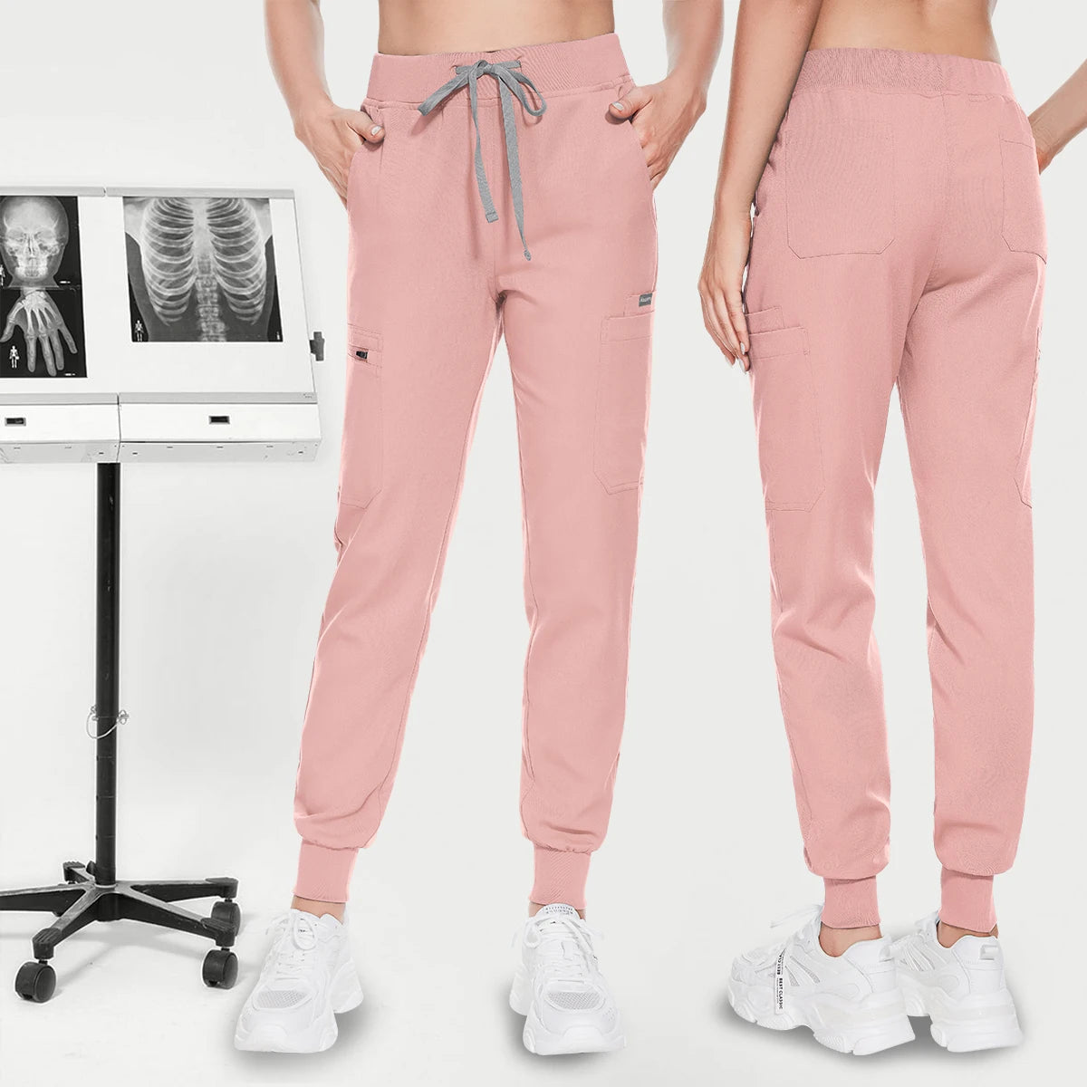 model wearing scrub pant standing next to an xray machine. jogger-style scrub pants with front side and back pockets. Elastic waistband with adjustable drawstrings.